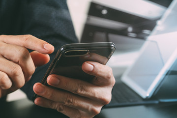 close up of businessman hand working with smart phone and laptop and digital tablet computer in modern office
