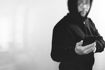 hipster male in a hood using mobile phone,front view,black and white