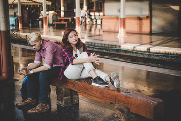 Obraz na płótnie Canvas Young attractive hipster couple sitting and waiting for the train to go traveling. Travel concept.