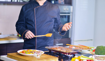 mature chef preparing a meal with various vegetables and meat