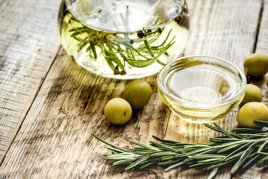 Bottle with olive oil and herbs on wooden background