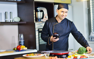 mature chef preparing a meal with various vegetables and meat