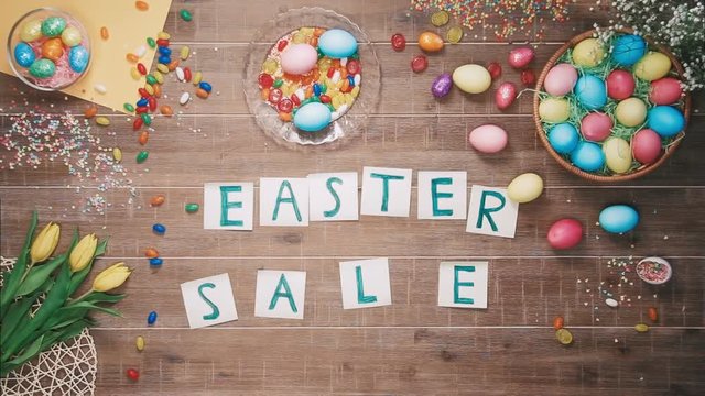 Man puts words Easter Sale on table decorated with easter eggs. Top view