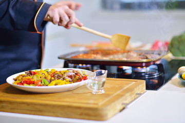 mature chef preparing a meal with various vegetables and meat
