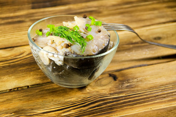 Marinated carp in glass bowl on wooden table