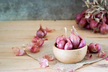 Abwaschbare Fototapete the shallots in bowl on old wooden table with old wallpaper and shallots bunch background © tumsubin