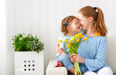 Happy mother's day! Child daughter congratulates moms and gives her a postcard and flowers
