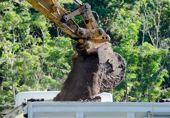Excavator bucket dumping soil into truck