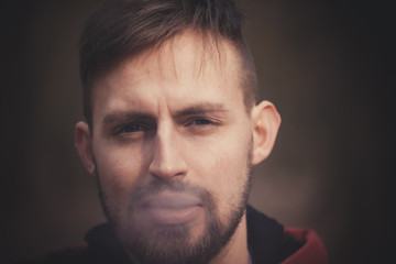 Fototapeta premium handsome stylish young man smoking outside in urban setting.