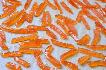 Cooking candied fruit. Grapefruit and orange peel drying on parchment paper.
