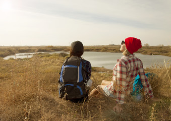 Two young woman sit on landscape