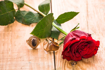 Red roses and engagement ring on wooden background