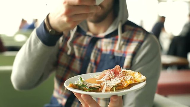 Man holding plate with slice of pizza and doing photo of this, steadycam shot
