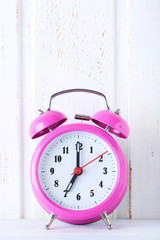 Pink alarm clock on white wall paneling background