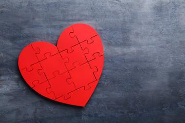 Red puzzle heart on grey wooden background