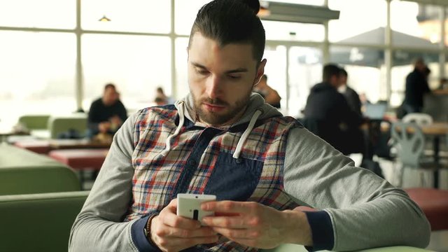 Man looks irritated while waiting for someone in the cafe, steadycam shot
