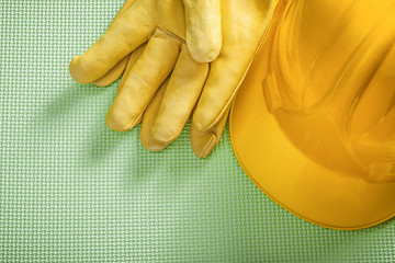 Yellow building helmet protective gloves on green background con