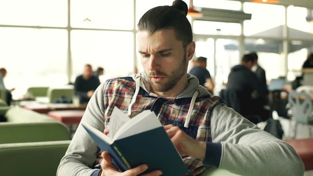 Man stops reading book in the cafe because of painful headache, steadycam shot
