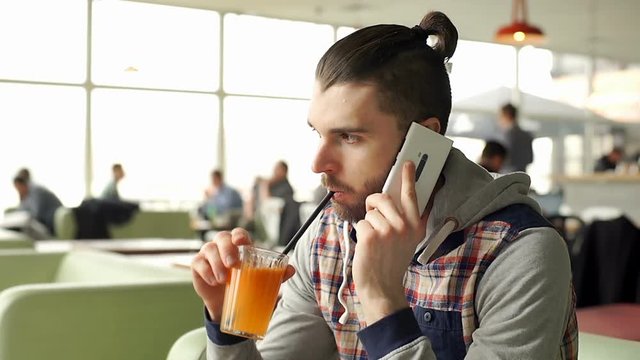 Man with top knot hairstyle wearing hoodie and chatting on cellphone, steadycam shot
