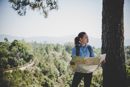 Young woman backpacker hiker reading map hiking trip. Relaxing on holiday.