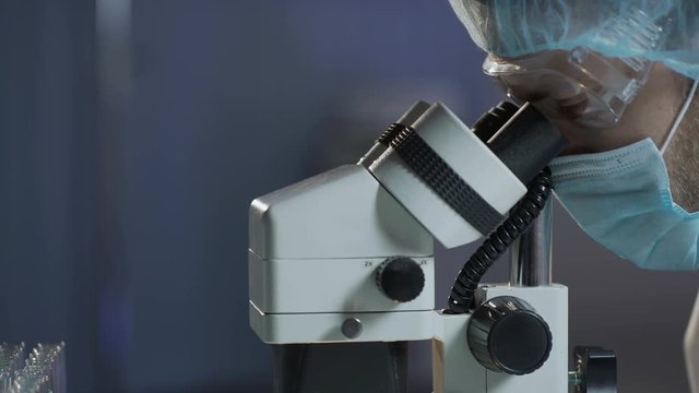 Neurosurgeon carrying out surgery on brain, looking in microscope, microsurgery