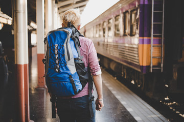Fototapeta premium Young hipster tourist with backpack on the train station. Holiday tourist concept.