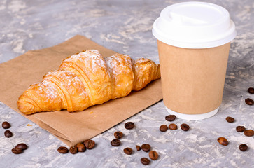 Coffee to go in a paper cup with croissants