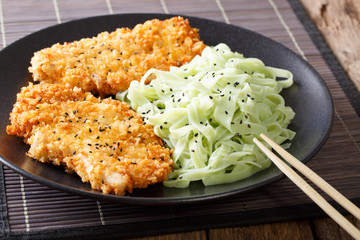 Asian food: steak in breaded Panko and green noodles with sesame close-up. horizontal