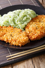 steak in breadcrumbs Panko and green noodles with sesame close-up. Vertical