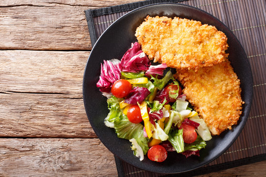 Chicken steak in breading Panko and fresh salad close-up on the table. horizontal top view
