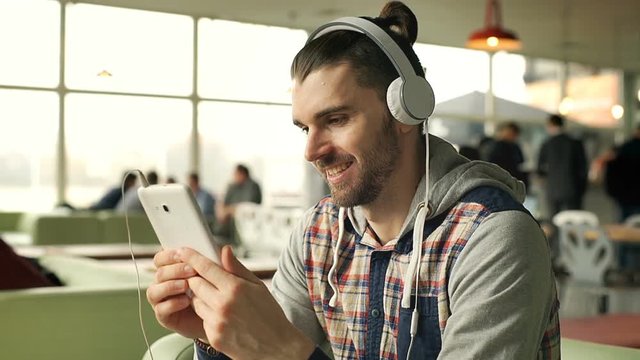 Man looks absorbed and laughs while watching something on tablet, steadycam shot
