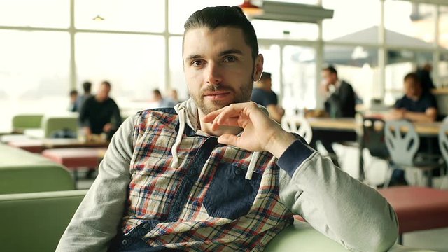 Handsome man relaxing in the cafe and smiling to the camera, steadycam shot
