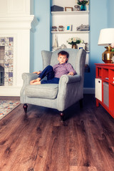 Portrait of a boy sitting in a chair in the room