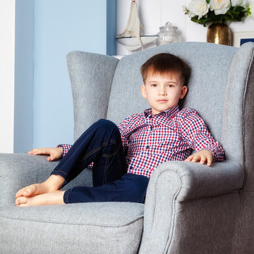 Portrait of a boy sitting in a chair in the room