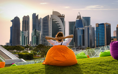 Frau auf Sitzkissen vor der Skyline von Doha, Katar