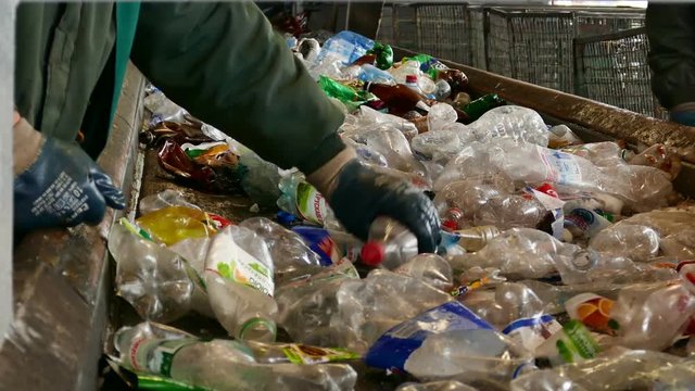 Workers sort garbage for recycling at a waste recycling plant