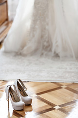 Fototapeta na wymiar White shoes stand before bride in wedding dress