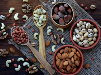 A composition from different varieties of nuts on a wooden background - almonds, cashews, peanuts, walnuts, hazelnuts, pistachios.