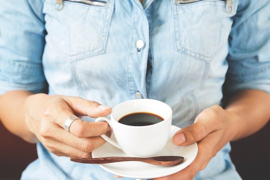 Young woman in blue jeans holding cup of hot coffee, Lifestyle concept