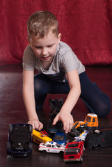 Many toy cars, little boy playing on the floor,