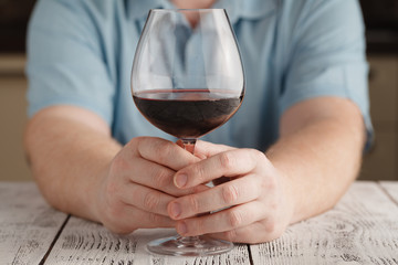 middle age man holding and looking in a glass of wine