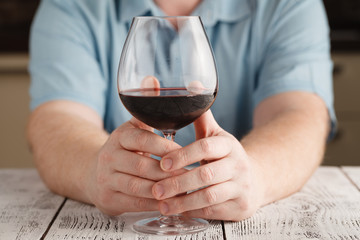 man sitting at table having a glass of red wine