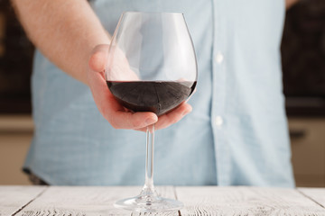 leisure, drinks and lifestyle concept - close up of male hand holdind glass of red wine