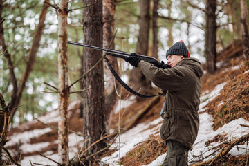 Fototapeta premium male hunter ready to hunt, holding gun and walking in forest.