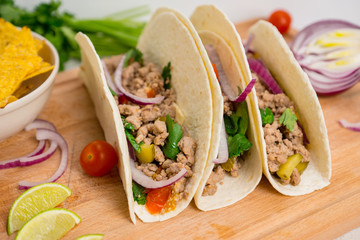 Mexican tacos with pork, pepper and tomatoes on the white wooden background. Shallow depth of field.