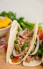 Mexican tacos with pork, pepper and tomatoes on the white wooden background. Shallow depth of field.
