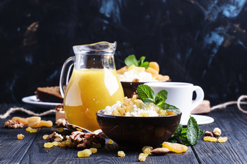 Breakfast with cottage cheese, dried fruits, nuts, juice, coffee and toast, dark background,...
