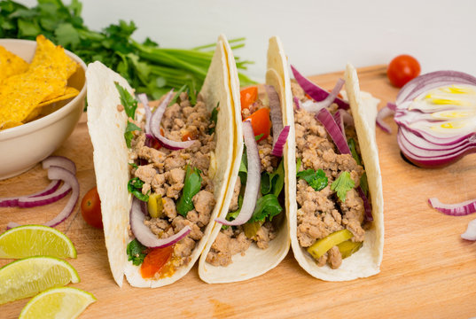 Mexican tacos with pork, pepper and tomatoes on the white wooden background. Shallow depth of field.