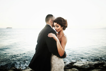 Groom holds in his hands awesome brunette bride in dress with silver threads