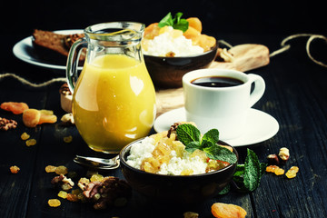 Breakfast with cottage cheese, dried fruits, nuts, juice, coffee and toast, dark background, selective focus